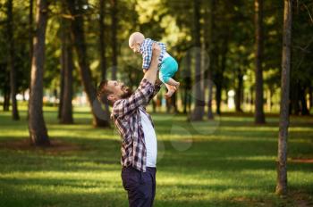 Father and little baby walks in summer park. Dad with male kid on lawn, picnic with child on plaid in the forest, family happiness