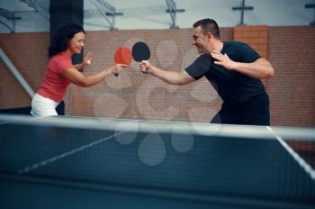Man and woman play table tennis, ping pong players. Couple playing table-tennis indoors, sport game with racket and ball, active healthy lifestyle