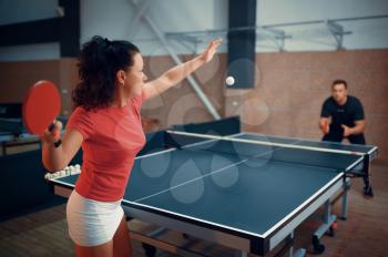 Woman hits the ball, table tennis, ping pong players. Couple playing table-tennis indoors, sport game with racket, active healthy lifestyle