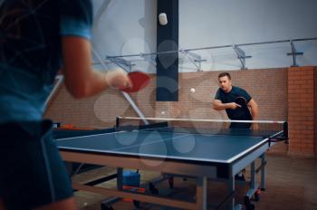 Two men play table tennis, ping pong players. Friends playing table-tennis indoors, sport game with racket and ball, active healthy lifestyle