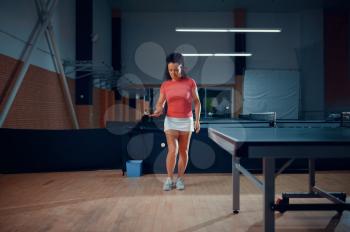 Woman hits a ball, table tennis training in gym, ping pong player. Sportive girl playing table-tennis indoors, sport game with racket, active healthy lifestyle