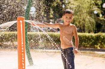 Little boy play on water playground in summer park. Child leisures in aquapark, aquatic adventure on vacations, child having fun in fountain