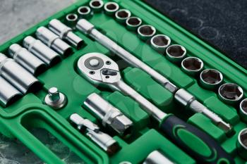 Set of spanners with ratchet in green plastic toolbox, closeup. Chrome vanadium wrench, professional toolkit, repair instrument for car service