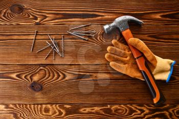 Screw nails, hammer and glove on wooden background, nobody. Professional instrument, carpenter equipment, fasteners, fastening and screwing tools