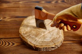 Male hand in glove holds an axe, closeup, wooden background. Professional instrument, carpenter equipment, woodworker tools