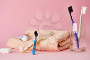 Oral care products, toothbrush, toothpaste and dental floss on towel, pink background, nobody. Morning healthcare procedures concept, toothcare