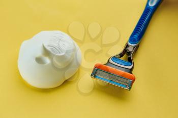 Skin care products, razor and shaving foam on yellow background, nobody. Healthcare procedures concept, blade or shaver
