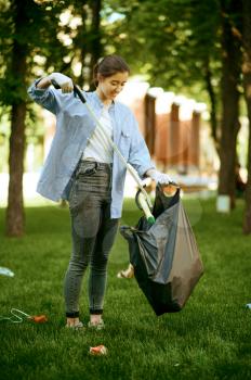 Young woman collects garbage in plastic bag in park, volunteering. Male person cleans forest, ecological restoration, eco lifestyle, trash collection and recycling, ecology care, environment cleaning