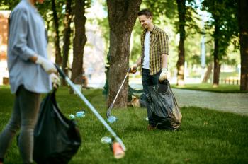 Two men collects plastic garbage in bags in park, volunteering. Male person cleans forest, ecological restoration, eco lifestyle, trash collection and recycling, ecology care, environment cleaning
