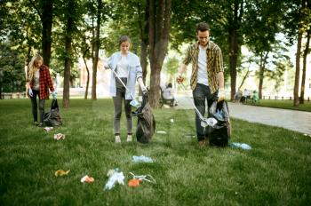Young people collects trash in plastic bags in park, volunteering. Volunteers cleans forest, ecological restoration, garbage collection and recycling, ecology care, environment cleaning