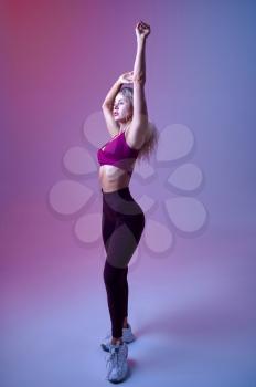Young sexy woman with slim body poses in studio, neon background. Sportswoman at the photo shoot, sport concept, active lifestyle