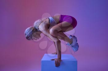 Sportswoman doing balance exercise in studio, neon background. Fitness woman at the photo shoot, sport concept, active lifestyle motivation
