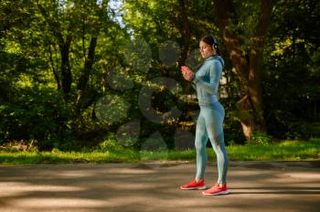 Morning fitness training in park, smiling woman in headphones. Female runner goes in for sports at sunny day, healthy lifestyle, jogger on outdoors workout