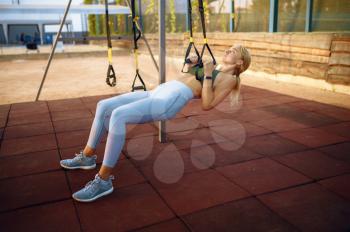 Woman doing exercise with ropes on sports ground outdoors. Slim female person in sportswear, outside fitness training, fit workout