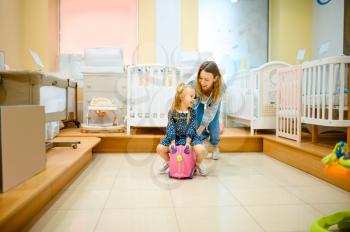 Mother and little daughter play in kid's store. Mom and adorable girl near the showcase in children's shop, happy childhood, family makes a purchase in market