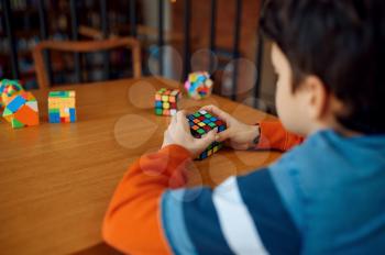 Little boy holds puzzle cube, selective focus on hand. Toy for brain and logical mind training, creative game, solving of complex problems