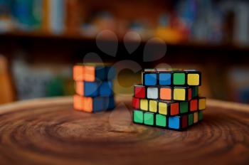 Classical colorful puzzle cubes on wooden stump, closeup view, nobody. Toy for brain and logical mind training, creative game, solving of complex problems