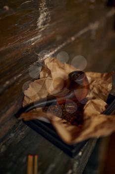 Smoking pipe and a pile of tobacco on wooden table, closeup view, nobody. Tobacco smoke culture, specific flavor. Smoker tools