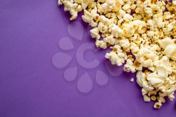 Popcorn border isolated on purple background, top view. Pop corn texture, tasty wallpaper design, movie or cinema food concept