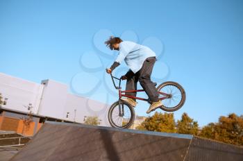 Bmx biker doing trick on ramp,teenager on training in skatepark. Extreme bicycle sport, dangerous cycle exercise, risk street riding, biking in summer park
