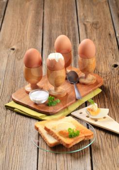 Boiled eggs in wooden eggcups with toast