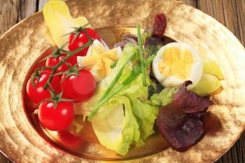 Fresh vegetables and boiled eggs on gold plate