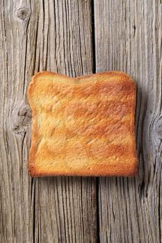 Slice of toasted bread on rough wood