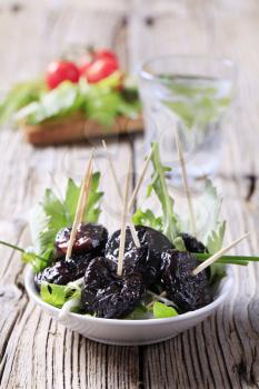 Glazed prunes on a nest of salad greens 