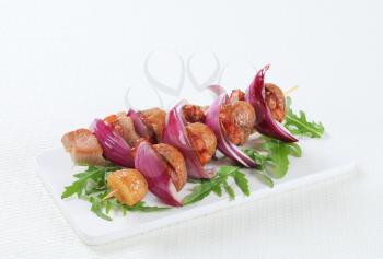 Pork and bacon skewers with potatoes and Spanish onion