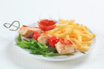 Chicken skewer with French fries and ketchup