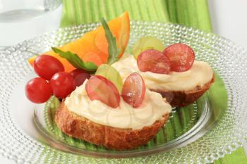 Slices of bread roll with cheese spread and grapes