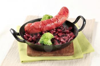 Sausage, beans and broccoli on a black pan 