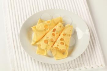 Thin slices of Swiss cheese on a plate