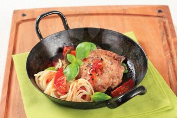 Pan fried meat patty with tomatoes and spaghetti