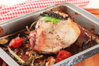 Roast pork with vegetables and gravy in a baking pan