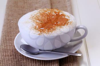Cup of cappuccino with rich milk froth and nutmeg on top