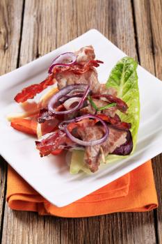 Meat skewer with crispy rashers of bacon and vegetables