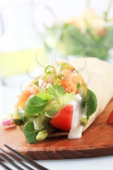 Tortilla filled with fresh vegetables and smoked salmon 