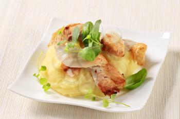 Pieces of roasted chicken on bed of mashed potato