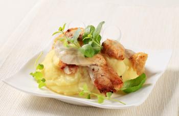 Pieces of roasted chicken on bed of mashed potato