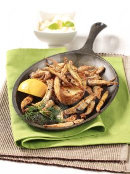 Crispy fried anchovies and roast potato on cast iron pan