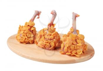 Raw chicken drumsticks coated with corn flakes
