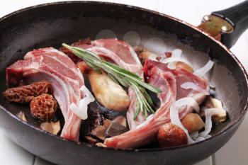 Lamb chops and mushrooms on a frying pan