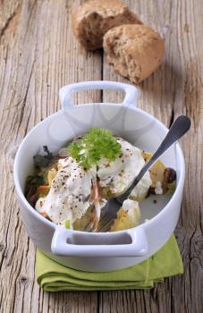 Potatoes and mushrooms topped with sour cream in a casserole dish
