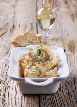 Mustard potato salad sprinkled with strips of ham, chives and cracklings