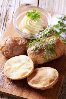 Baked potatoes, butter and salt on a cutting board