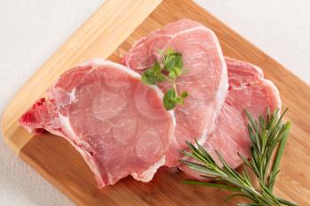 Raw pork chops on a cutting board
