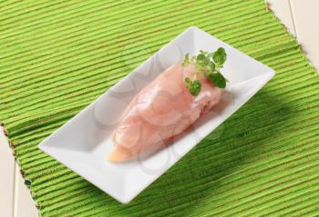 Raw chicken breast in a white porcelain dish