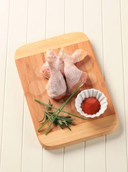 Raw chicken drumsticks on a cutting board