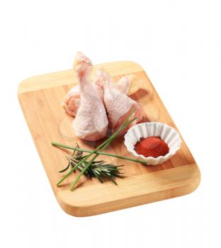 Raw chicken drumsticks on a cutting board